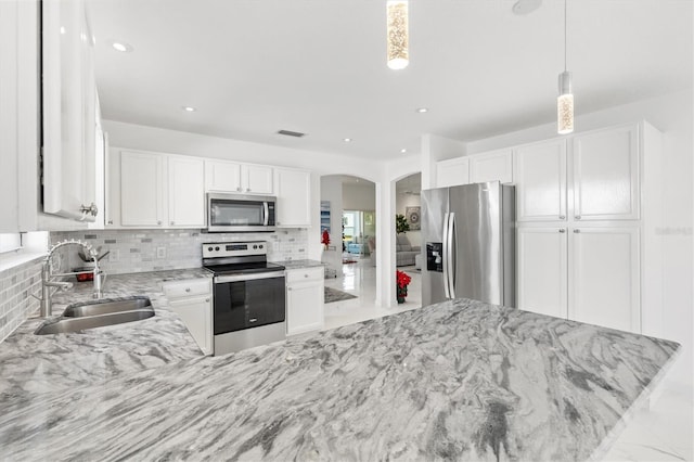 kitchen with white cabinetry, sink, stainless steel appliances, tasteful backsplash, and pendant lighting