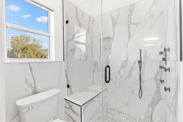 bathroom featuring a shower with door and toilet