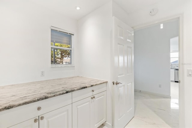 kitchen featuring white cabinets, light stone counters, and dishwasher