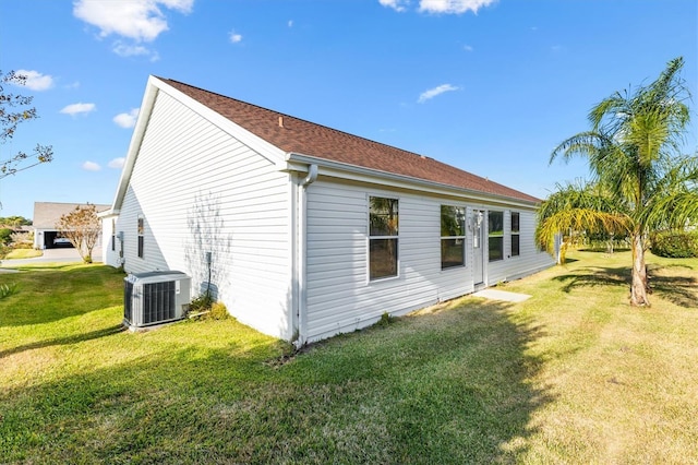 view of side of home with central AC unit and a yard