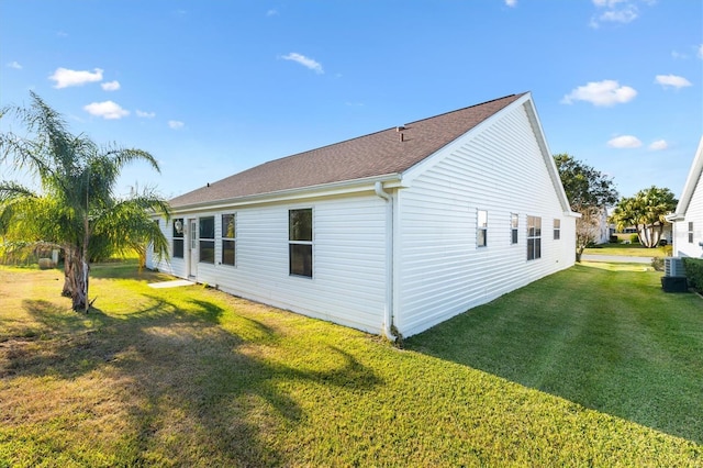 view of side of home with central AC unit and a yard