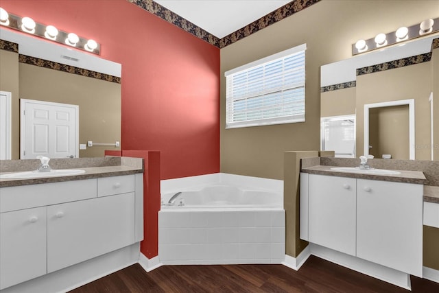 bathroom featuring tiled tub, vanity, and hardwood / wood-style flooring