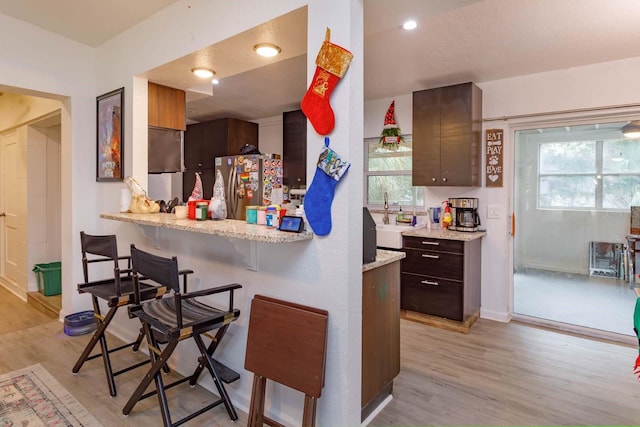 kitchen featuring a kitchen breakfast bar, light hardwood / wood-style floors, and stainless steel refrigerator