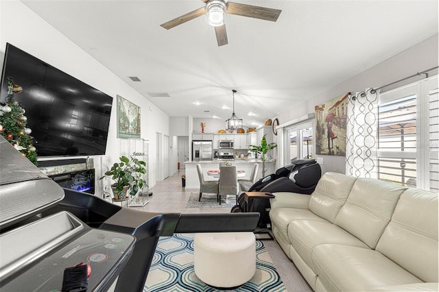 tiled living room with ceiling fan with notable chandelier