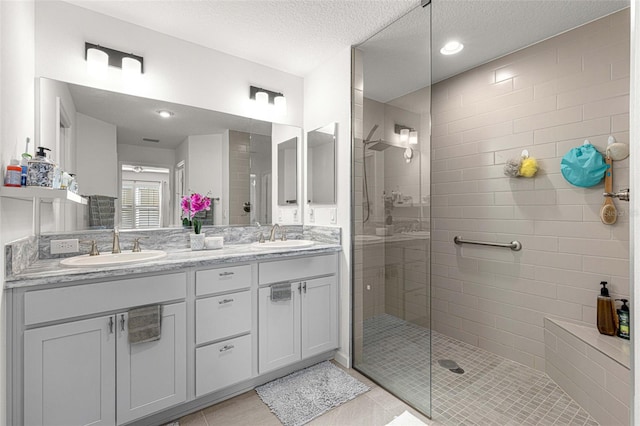 bathroom featuring tile patterned flooring, vanity, a textured ceiling, and tiled shower