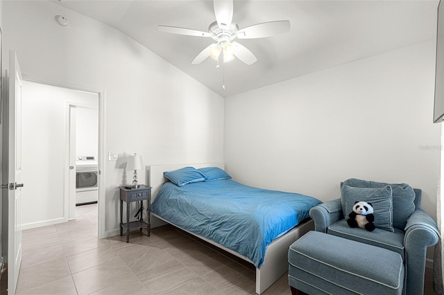 bedroom with ceiling fan, washer / dryer, light tile patterned floors, and vaulted ceiling