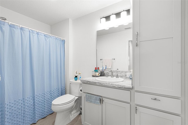 bathroom featuring vanity, a textured ceiling, and toilet