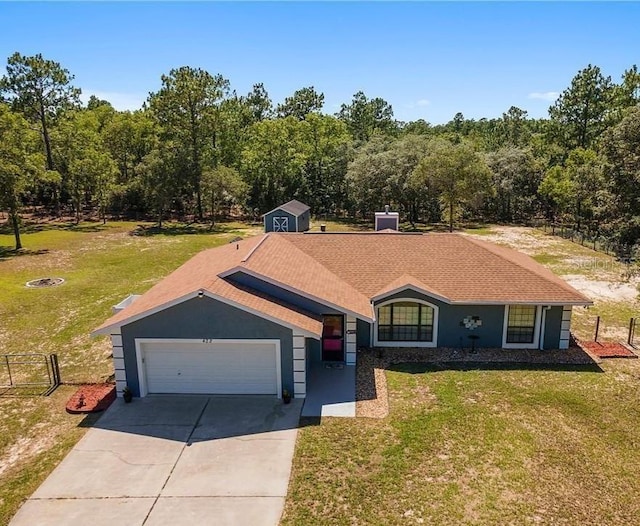 ranch-style home featuring a garage, a storage shed, and a front lawn