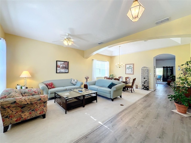 living room with ceiling fan with notable chandelier and light wood-type flooring