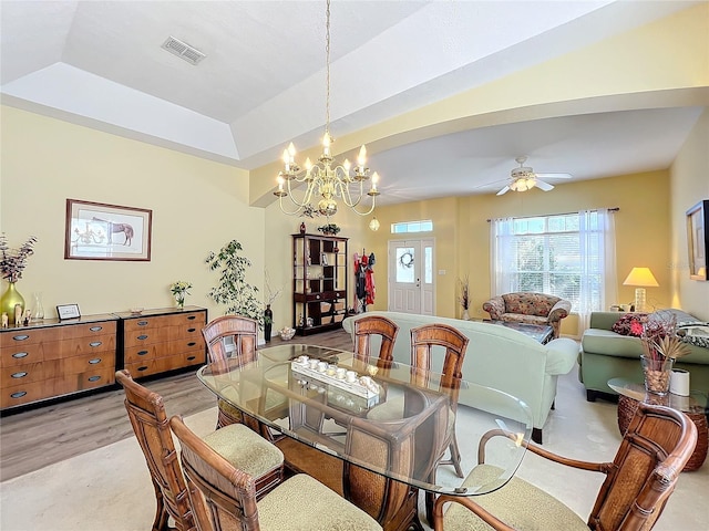 dining space featuring a tray ceiling and ceiling fan with notable chandelier