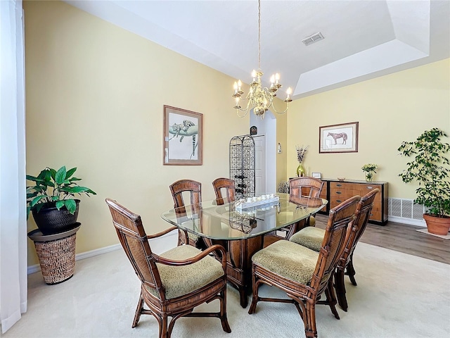 dining room featuring light carpet, an inviting chandelier, and a tray ceiling