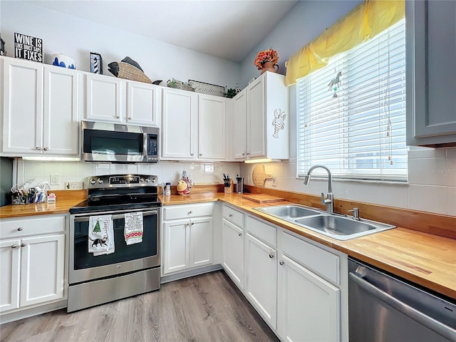 kitchen with appliances with stainless steel finishes, sink, white cabinets, and butcher block countertops