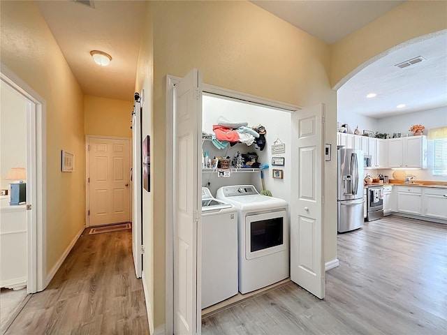 laundry room with separate washer and dryer, light hardwood / wood-style floors, and a barn door