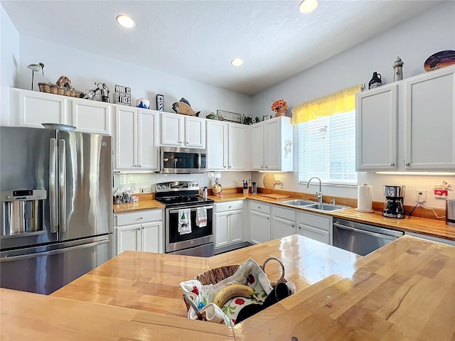 kitchen featuring white cabinetry, stainless steel appliances, sink, and wooden counters