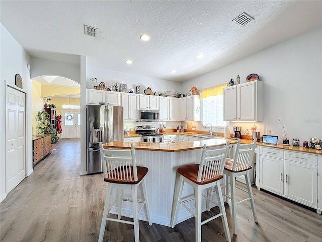 kitchen with sink, light hardwood / wood-style flooring, a breakfast bar, stainless steel appliances, and white cabinets