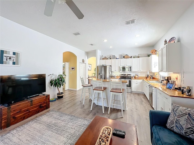 kitchen with appliances with stainless steel finishes, a breakfast bar, white cabinetry, sink, and a center island