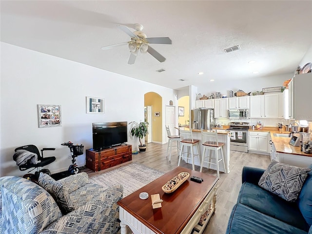 living room with ceiling fan, sink, and light wood-type flooring