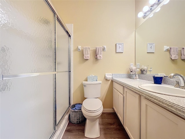 bathroom with hardwood / wood-style flooring, vanity, toilet, and a shower with shower door