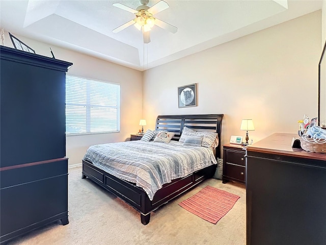 bedroom featuring ceiling fan, a raised ceiling, and light colored carpet