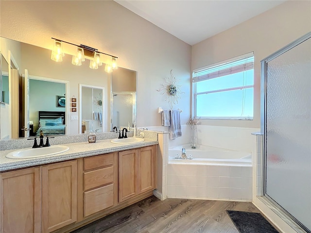 bathroom with wood-type flooring, shower with separate bathtub, and vanity