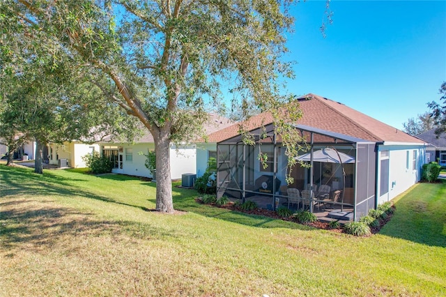 rear view of property with a lanai, central AC unit, and a lawn