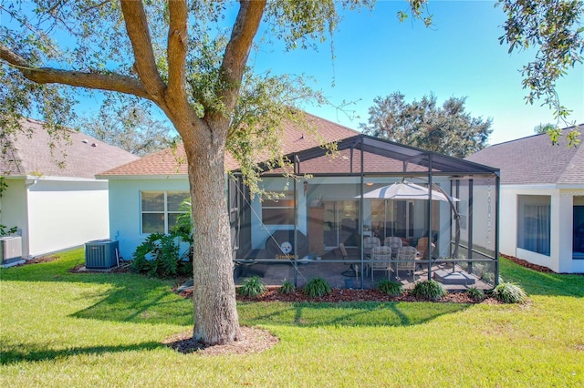 rear view of house with cooling unit, a yard, and a lanai