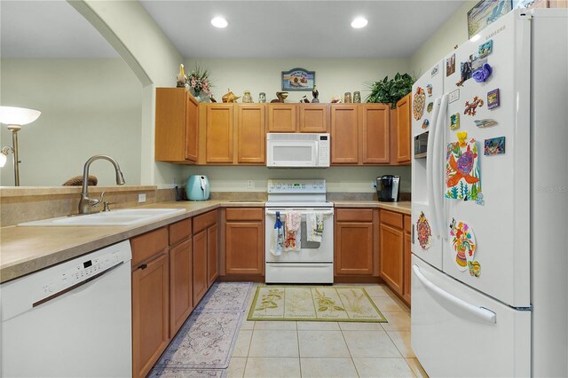 kitchen featuring light tile patterned floors, white appliances, and sink