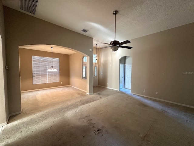 unfurnished living room with lofted ceiling, ceiling fan with notable chandelier, carpet, and a textured ceiling