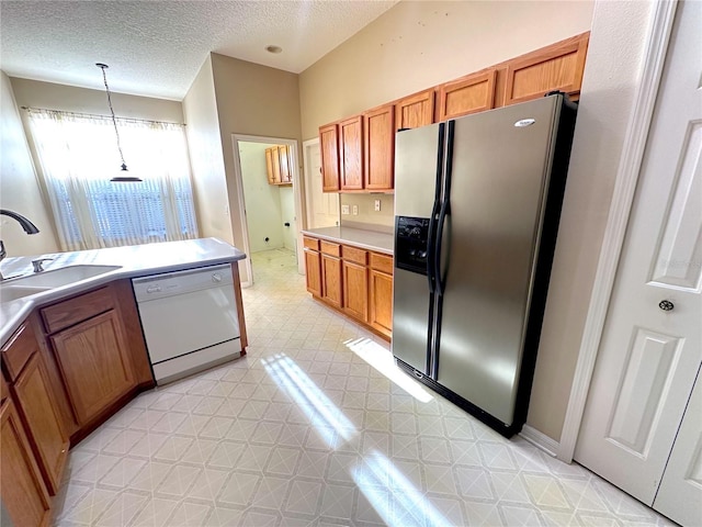 kitchen with white dishwasher, sink, a textured ceiling, decorative light fixtures, and stainless steel fridge with ice dispenser