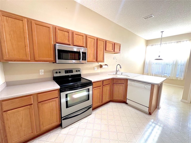 kitchen featuring kitchen peninsula, appliances with stainless steel finishes, a textured ceiling, sink, and hanging light fixtures