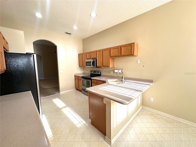 kitchen with kitchen peninsula, a textured ceiling, stainless steel appliances, and sink