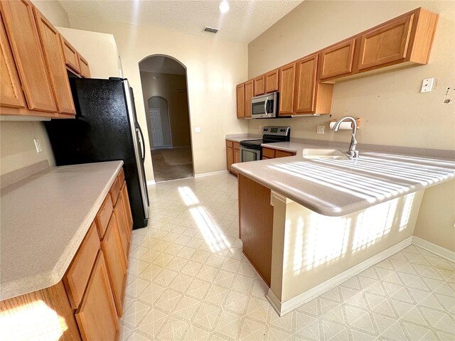 kitchen with sink, kitchen peninsula, a textured ceiling, and appliances with stainless steel finishes