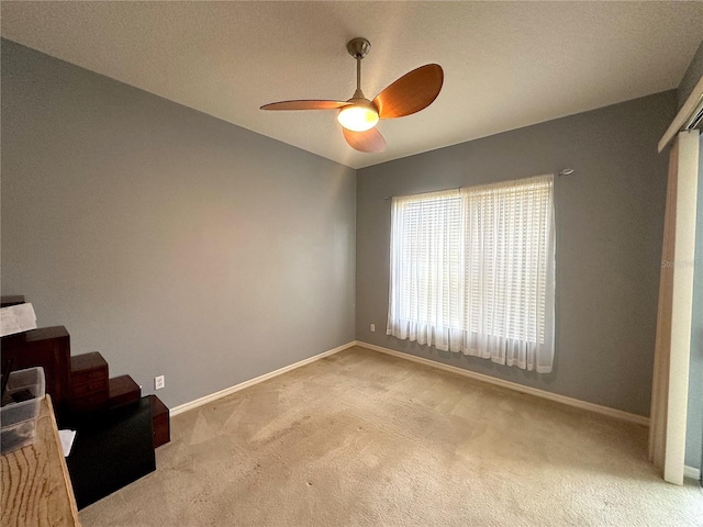 empty room with light carpet, ceiling fan, and a textured ceiling