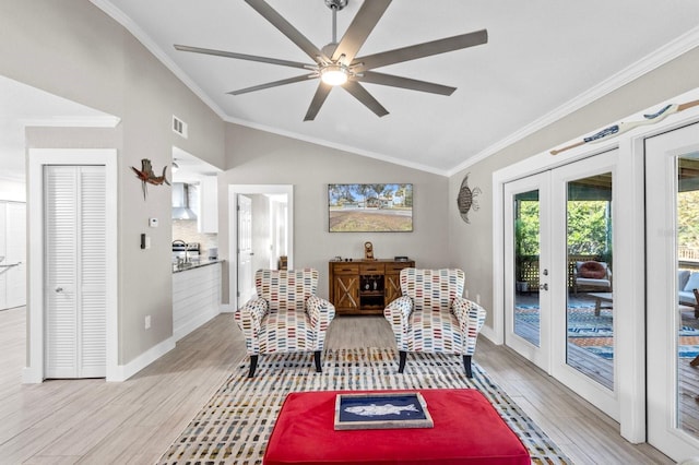 sitting room with crown molding, french doors, lofted ceiling, and light wood-type flooring