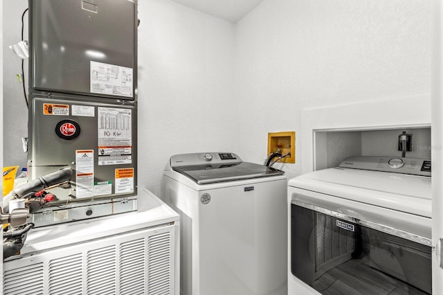 clothes washing area featuring heating unit and washer and clothes dryer