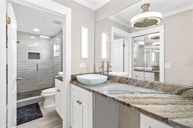 bathroom with vanity, toilet, a shower with shower door, and crown molding