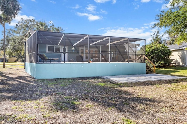 back of property featuring glass enclosure and a patio