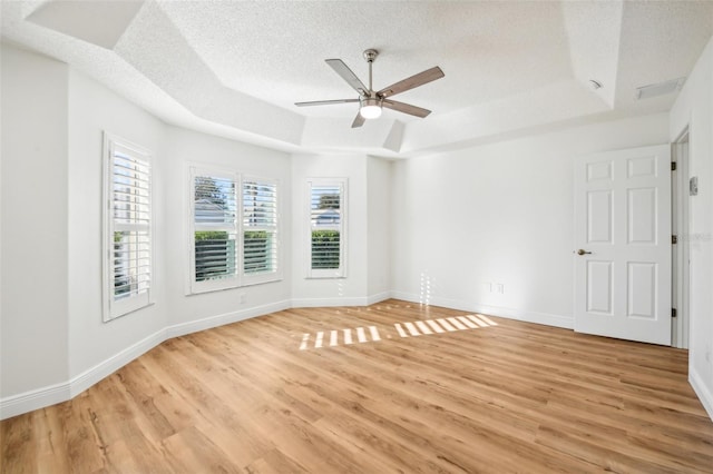 unfurnished room featuring a textured ceiling, light hardwood / wood-style floors, a raised ceiling, and ceiling fan