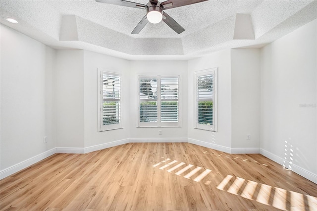 spare room featuring light wood-type flooring, a textured ceiling, and a wealth of natural light