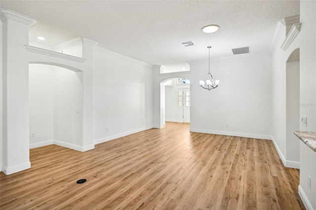 interior space with crown molding, light hardwood / wood-style flooring, a textured ceiling, and an inviting chandelier