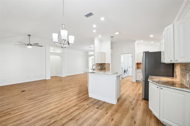 kitchen with white cabinets, pendant lighting, light wood-type flooring, and backsplash