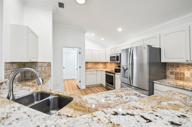 kitchen featuring stainless steel appliances, white cabinetry, tasteful backsplash, and sink