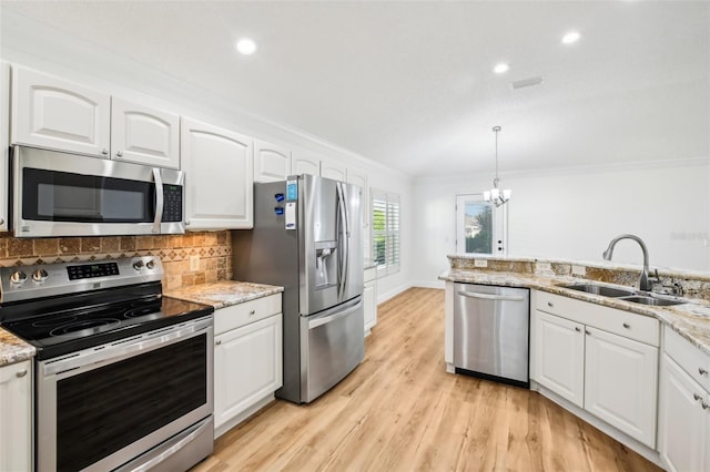 kitchen with light wood-type flooring, stainless steel appliances, sink, pendant lighting, and white cabinets