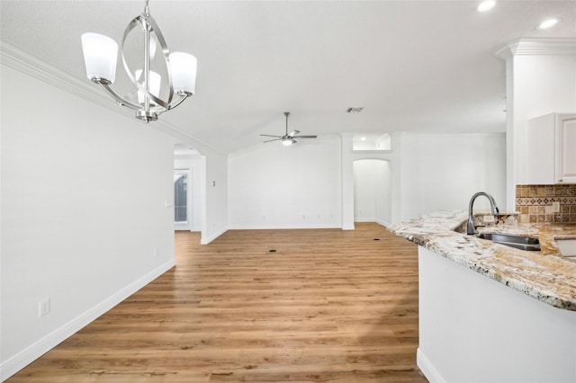 unfurnished dining area featuring ceiling fan with notable chandelier, crown molding, light wood-type flooring, and sink