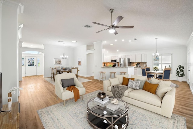 living room with a textured ceiling, ceiling fan with notable chandelier, light hardwood / wood-style floors, and crown molding