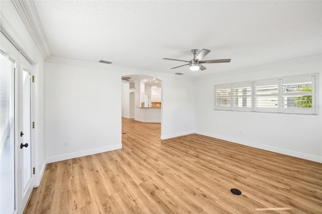 empty room featuring a textured ceiling, ceiling fan, light wood-type flooring, and crown molding