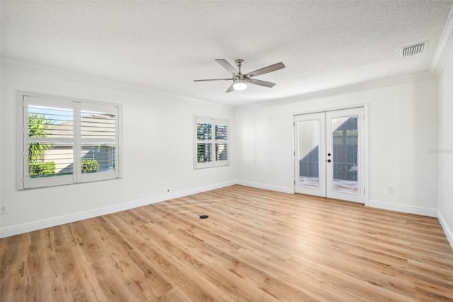 empty room featuring ceiling fan, french doors, light hardwood / wood-style flooring, crown molding, and a textured ceiling