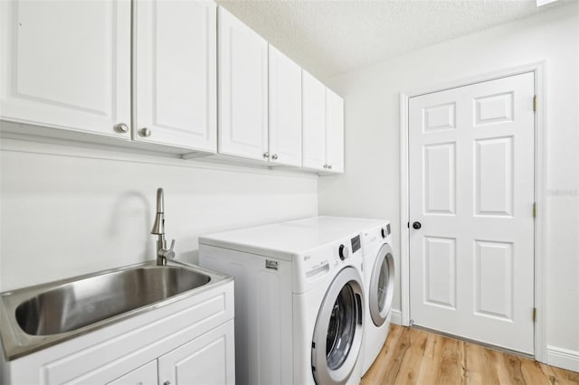 laundry room with cabinets, a textured ceiling, light hardwood / wood-style flooring, and sink