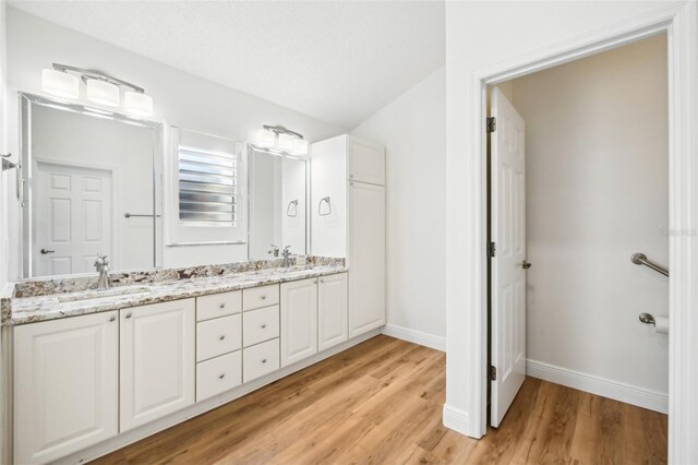 bathroom featuring hardwood / wood-style flooring, vanity, and vaulted ceiling