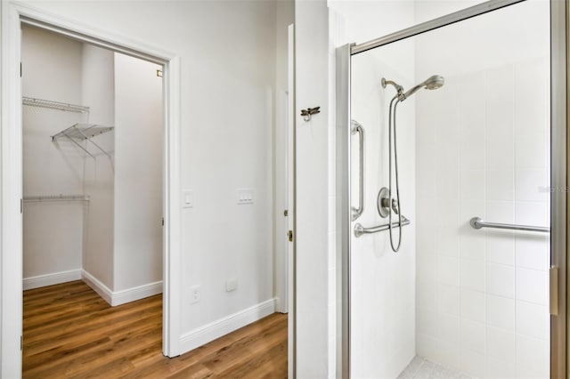 bathroom featuring a tile shower and wood-type flooring